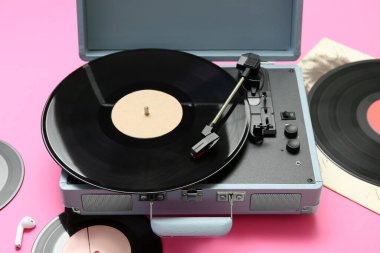 Pembe arka planda vinil diskleri olan kayıt çalar, yakın plan