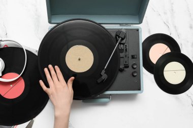 Beyaz arka planda vinil diskleri ve pikabı olan bir kadın.
