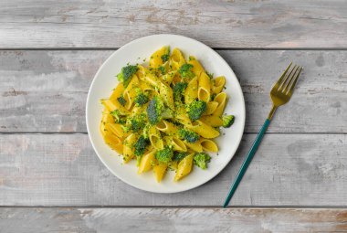 Gri ahşap arka planda lezzetli makarna ve brokoli tabağı.