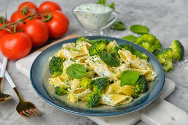 Gri arka planda lezzetli makarna ve brokoli tabağı.