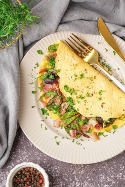 Gri grunge arka planda jambonlu ve yeşillikli lezzetli omlet.