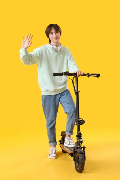 Adolescente Con Bicicleta Eléctrica Agitando Mano Sobre Fondo Amarillo —  Fotos de Stock
