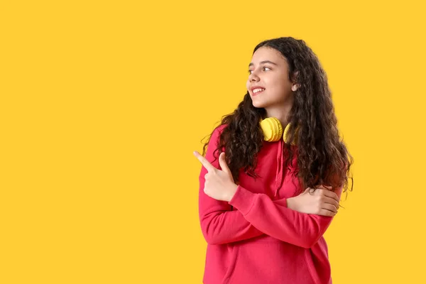 十代の女の子とともにヘッドフォン指す何かで黄色の背景 — ストック写真