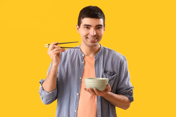 Jongeman Met Eetstokjes Kom Chinees Eten Gele Achtergrond — Stockfoto