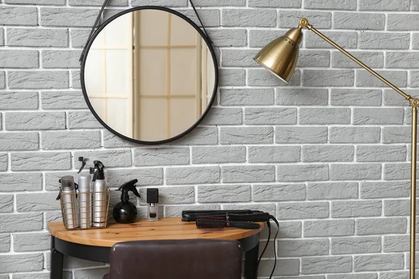 灰色のレンガの壁の近くのテーブルの上に異なる髪スプレーやアクセサリー — ストック写真