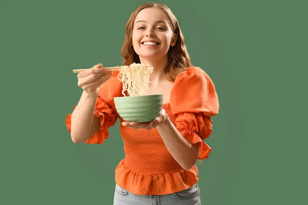 緑色の背景に中華麺のボウルを持つ若い女性 — ストック写真