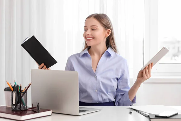 Young businesswoman with notebook and tablet computer in office. Balance concept