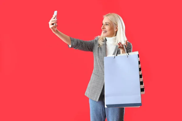 Donna Matura Con Cellulare Shopping Bag Scattare Selfie Sfondo Rosso — Foto Stock