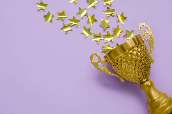 Gold cup with stars on lilac background, closeup