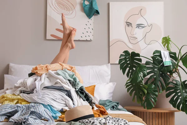 Woman with stack of dirty clothes on bed at home