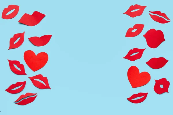Frame made of red paper lips and hearts on blue background