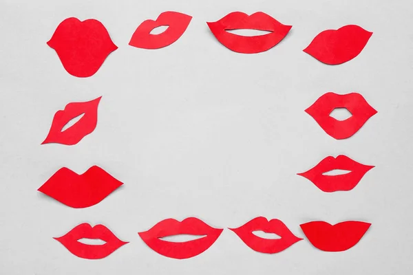 Frame made of red paper lips on light background