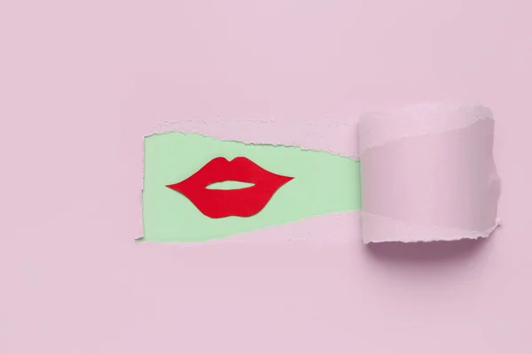 Red paper lips visible through hole in pink paper