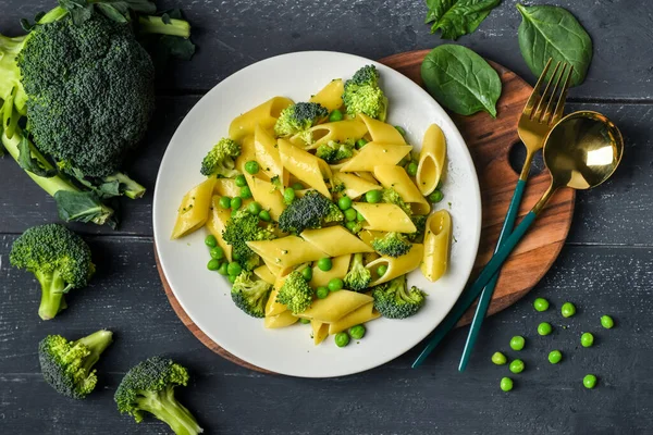 stock image Plate with tasty penne pasta and broccoli on dark wooden background