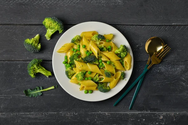 stock image Plate with tasty penne pasta and broccoli on dark wooden background