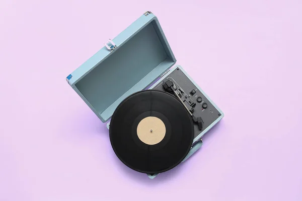 Record player with vinyl disk on lilac background