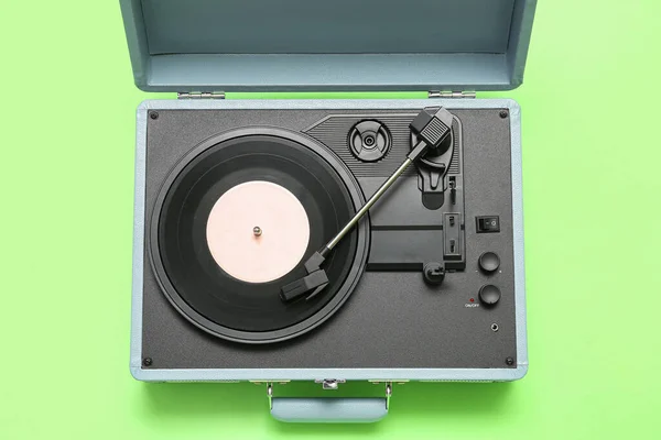 Record player with vinyl disk on green background