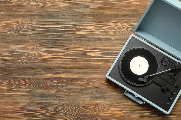 Record player with vinyl disk on wooden background