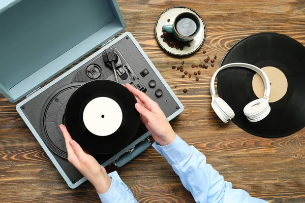 レコードディスクと木製の背景にレコードプレーヤーを持つ女性 — ストック写真