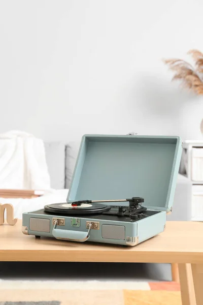 Record player with vinyl disk on table in room