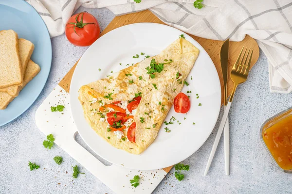 stock image Tasty omelet with tomatoes and parsley on light table