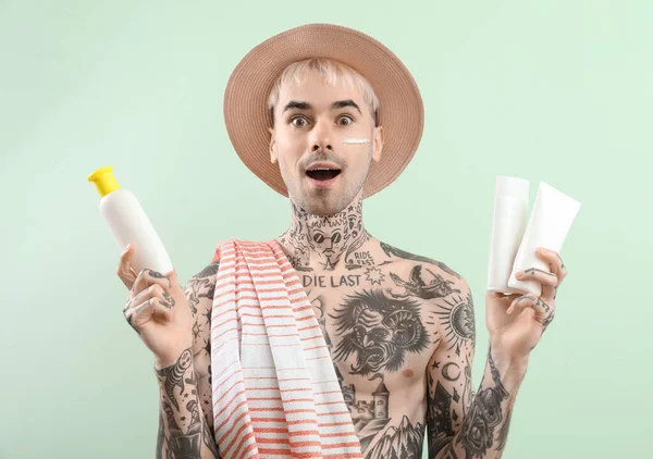 Överraskad Tatuerad Man Med Solkräm Krämer Ljusgrön Bakgrund — Stockfoto