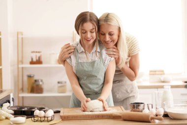 Kızıyla birlikte mutfakta hamur hazırlayan olgun bir kadın. Anneler Günü kutlaması