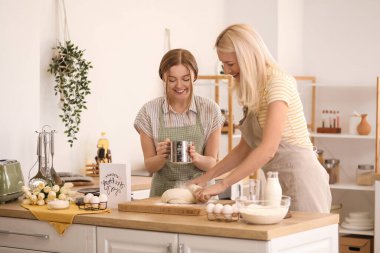 Kızıyla birlikte mutfakta hamur hazırlayan olgun bir kadın. Anneler Günü kutlaması