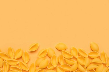 Sarı arka planda bir yığın çiğ koni makarnası.