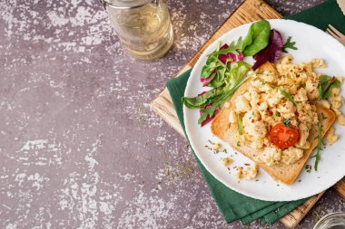 Lezzetli omletli sandviç ve gri arka planda salata.