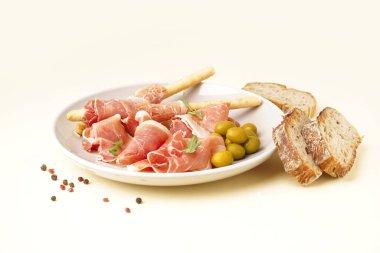 Sarı arka planda lezzetli jamon ve İtalyan Grissini tabağı.