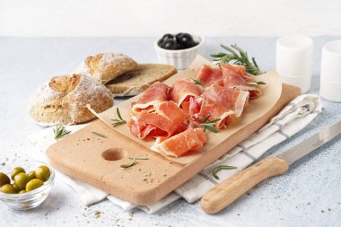 Hafif arka planda lezzetli jamon dilimleri olan ahşap tahta.