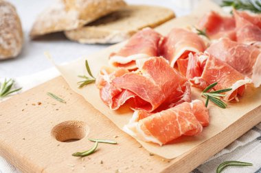 Masada lezzetli jamon dilimleri olan ahşap tahta, yakın plan.
