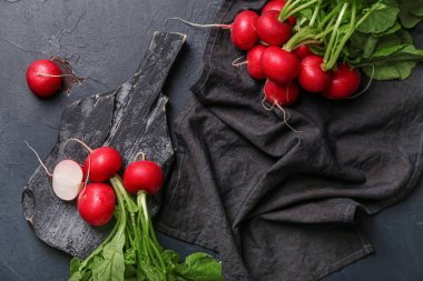 Koyu arkaplanda yeşil yapraklı olgun turp tahtası.