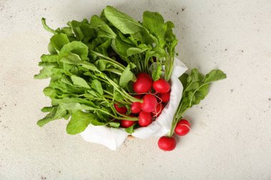 Açık arkaplanda yeşil yapraklı olgun turp sepeti.