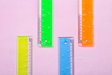 Pembe arka planda renkli plastik cetveller