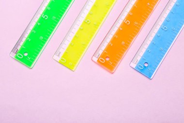 Pembe arka planda renkli plastik cetveller