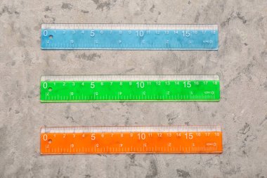 Gri grunge arka planında renkli plastik cetveller