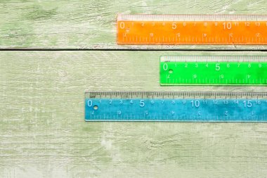 Yeşil ahşap arka planda renkli plastik cetveller