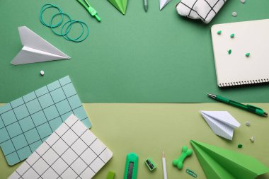 Renkli arka planda not defterlerinden, kırtasiye malzemelerinden ve kağıt uçaklardan oluşan çerçeve