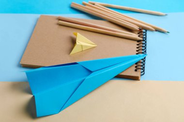 Renkli arka planda kırtasiye malzemeleri ve kağıt uçaklar ile kompozisyon