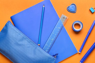 Turuncu arkaplanda defter ve kırtasiye malzemeleri