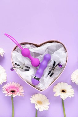 Gift box with sex toys and flowers on lilac background clipart