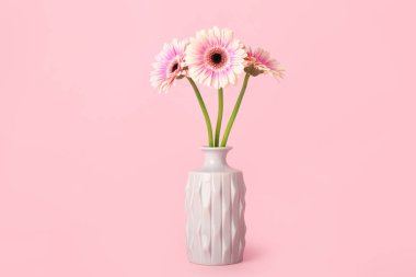 Pembe arka planda Gerbera çiçekleri olan vazo