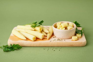 Ahşap tahta kesim ve zeytin arkaplanda konserve mısır koçanı.