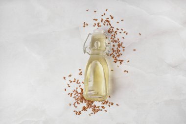 Keten yağı ve hafif arka planda tohumlarla dolu bir şişe.