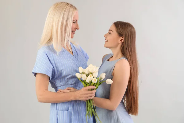 Junge Frau Begrüßt Ihre Mutter Mit Tulpen Auf Grauem Hintergrund — Stockfoto