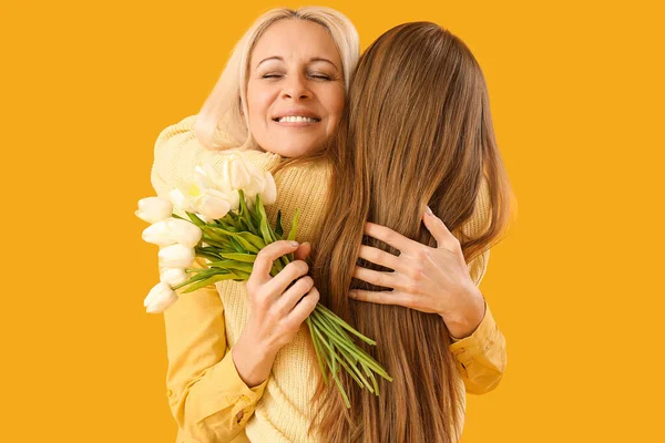 Mujer Madura Con Tulipanes Abrazando Hija Sobre Fondo Naranja Celebración —  Fotos de Stock