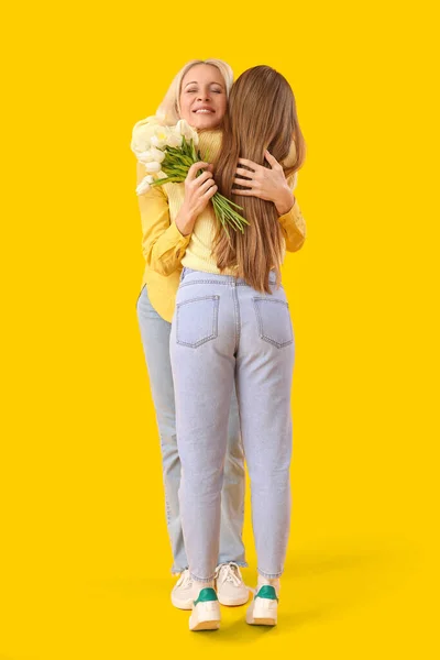 Reife Frau Mit Tulpen Umarmt Ihre Tochter Auf Orangefarbenem Hintergrund — Stockfoto