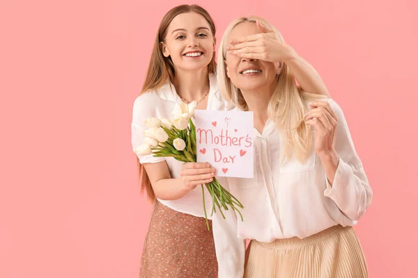Mujer Joven Saludando Madre Con Tulipanes Tarjeta Sobre Fondo Rosa —  Fotos de Stock